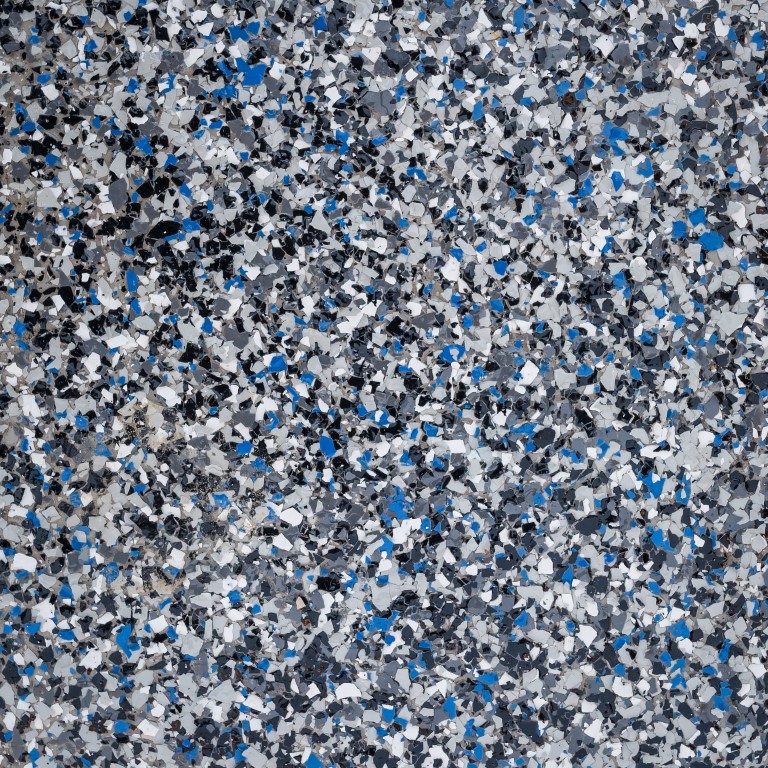 This image shows a close-up of a speckled surface with varying shapes in blue, black, white, and gray, possibly a material like terrazzo flooring.