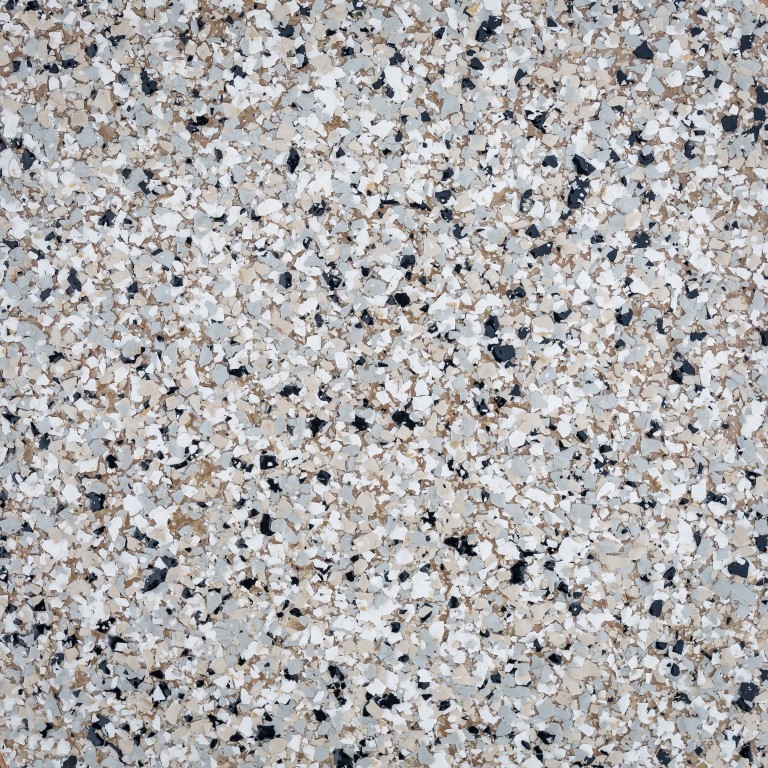 The image displays a close-up of a terrazzo floor with a speckled pattern of black, white, and beige fragments embedded in a neutral matrix.