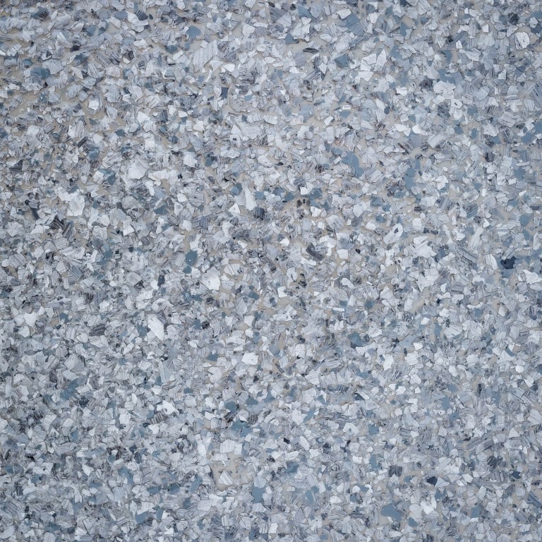 This image shows a close-up of numerous small, shattered glass pieces scattered densely, creating a textured pattern with variations of white and pale blue.