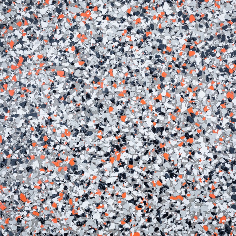 The image shows a granular mixture with shades of gray, white, black, and vibrant orange particles, possibly representing a type of granulated material.