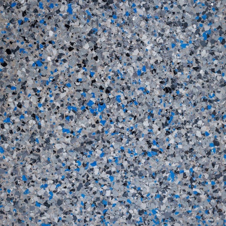 The image shows a speckled pattern of various shades of gray, black, white, and blue particles densely packed in a random mosaic.